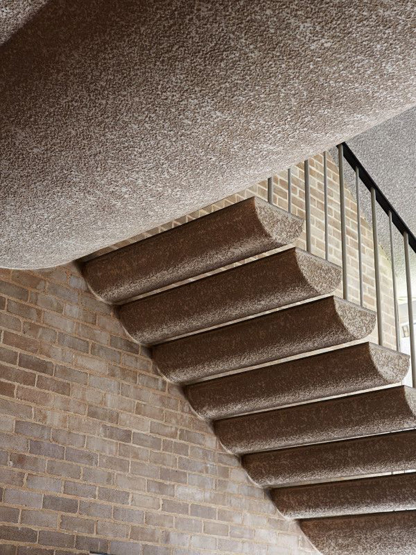 Concrete staircase with a textured ceiling and brick wall.