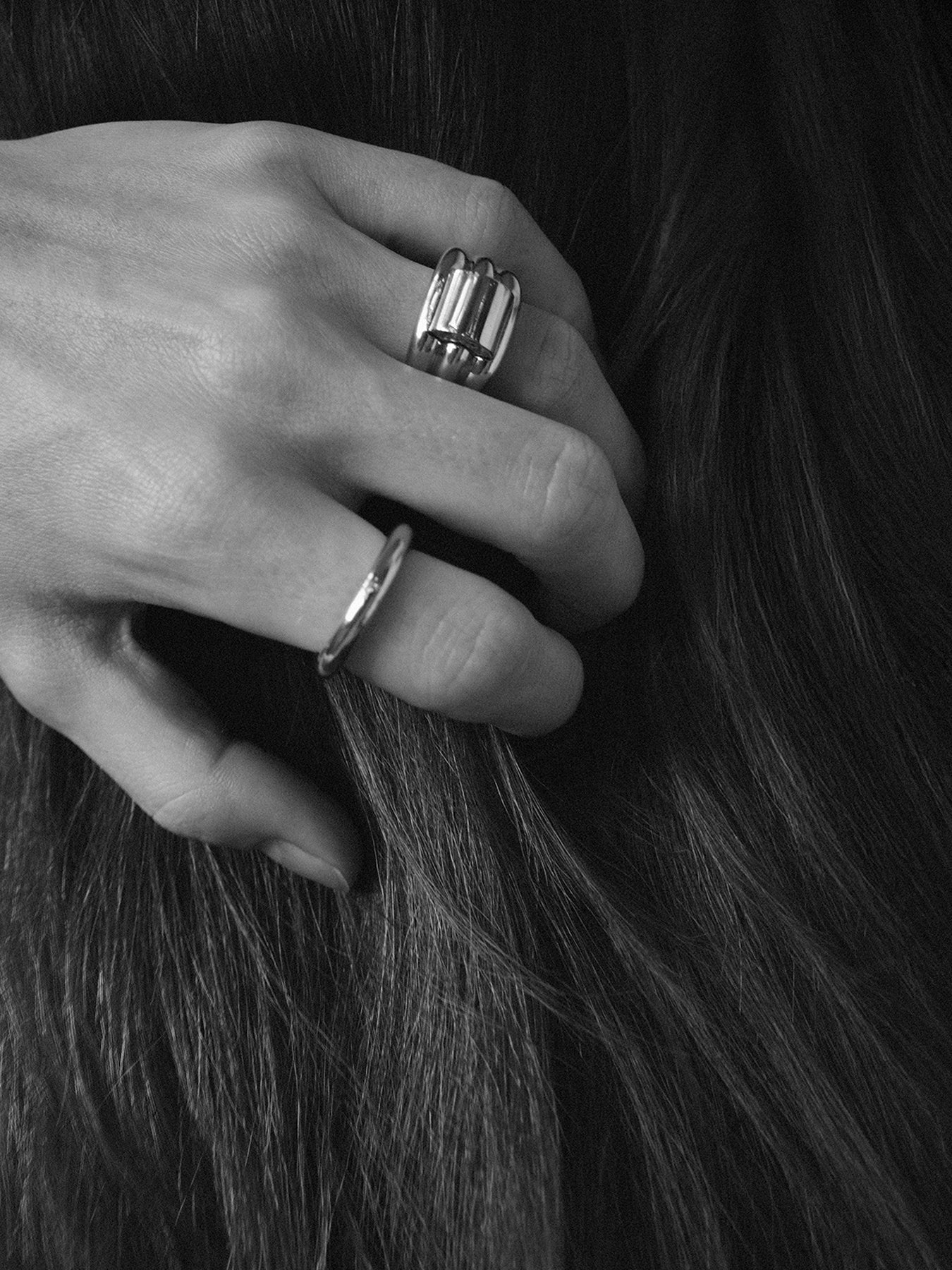Close-up of a hand with two rings holding dark hair