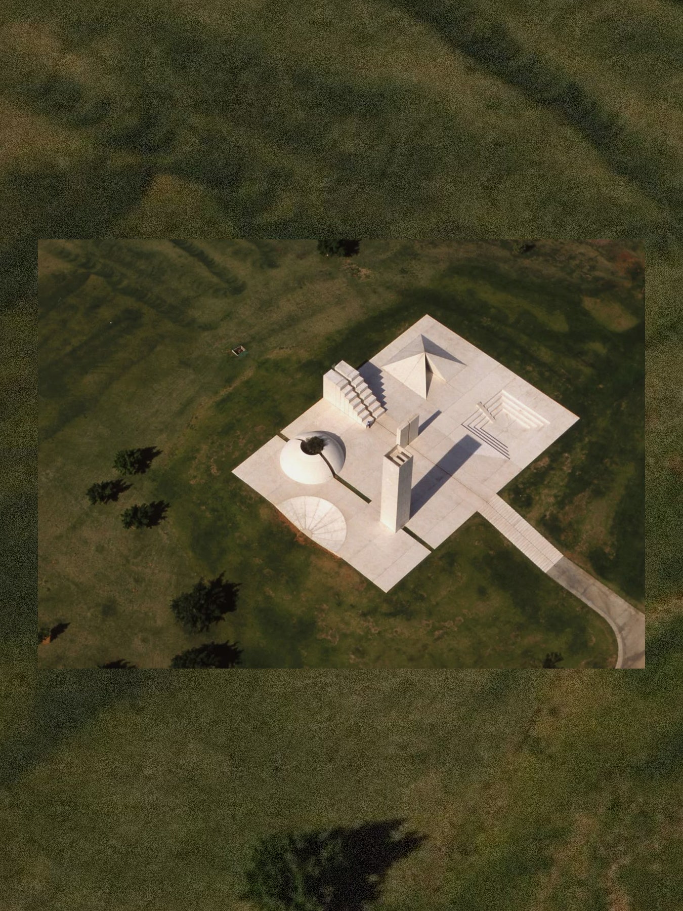 Aerial view of a sculpture with a geometric design on a green landscape