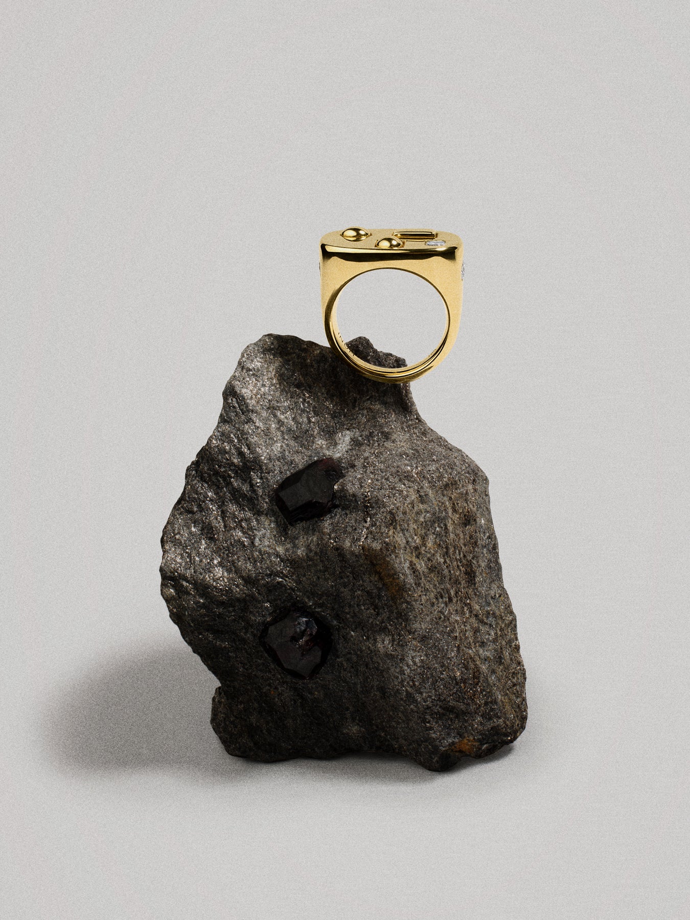 Gold ring on a dark gray rock against a light gray background