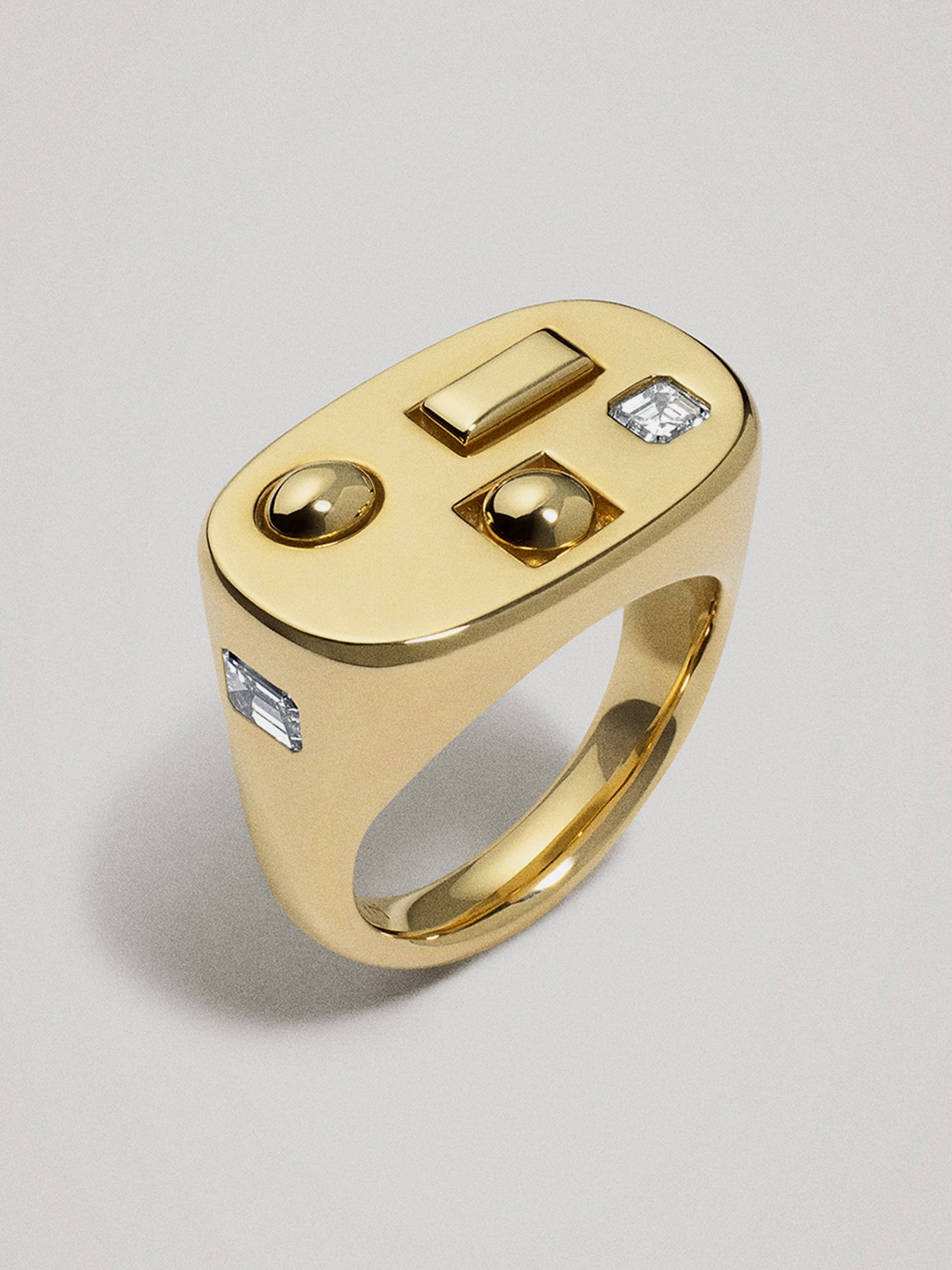 Gold ring with embedded diamonds and shapes on a light gray background