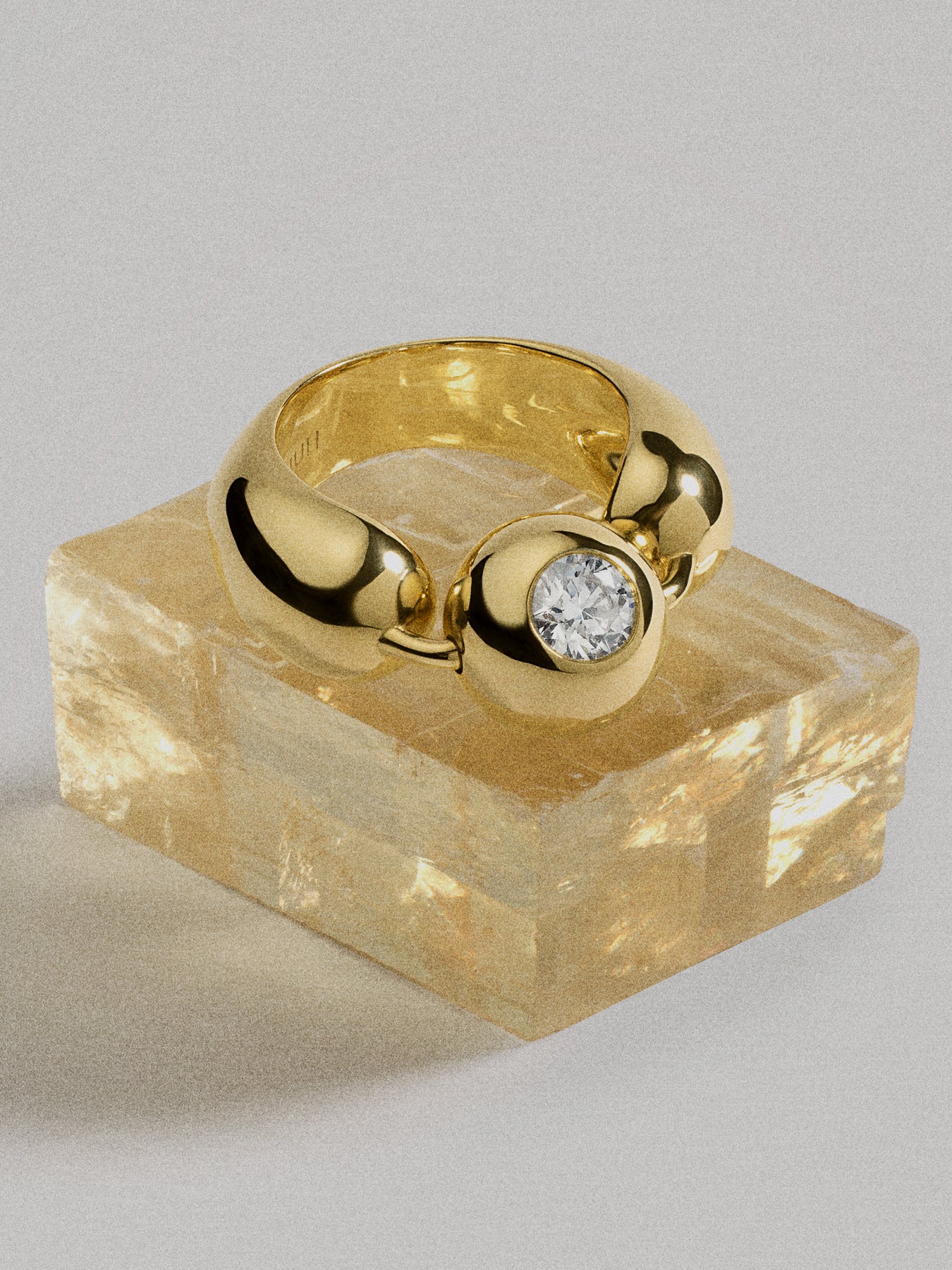 Gold ring with a diamond on a stone block against a gray background