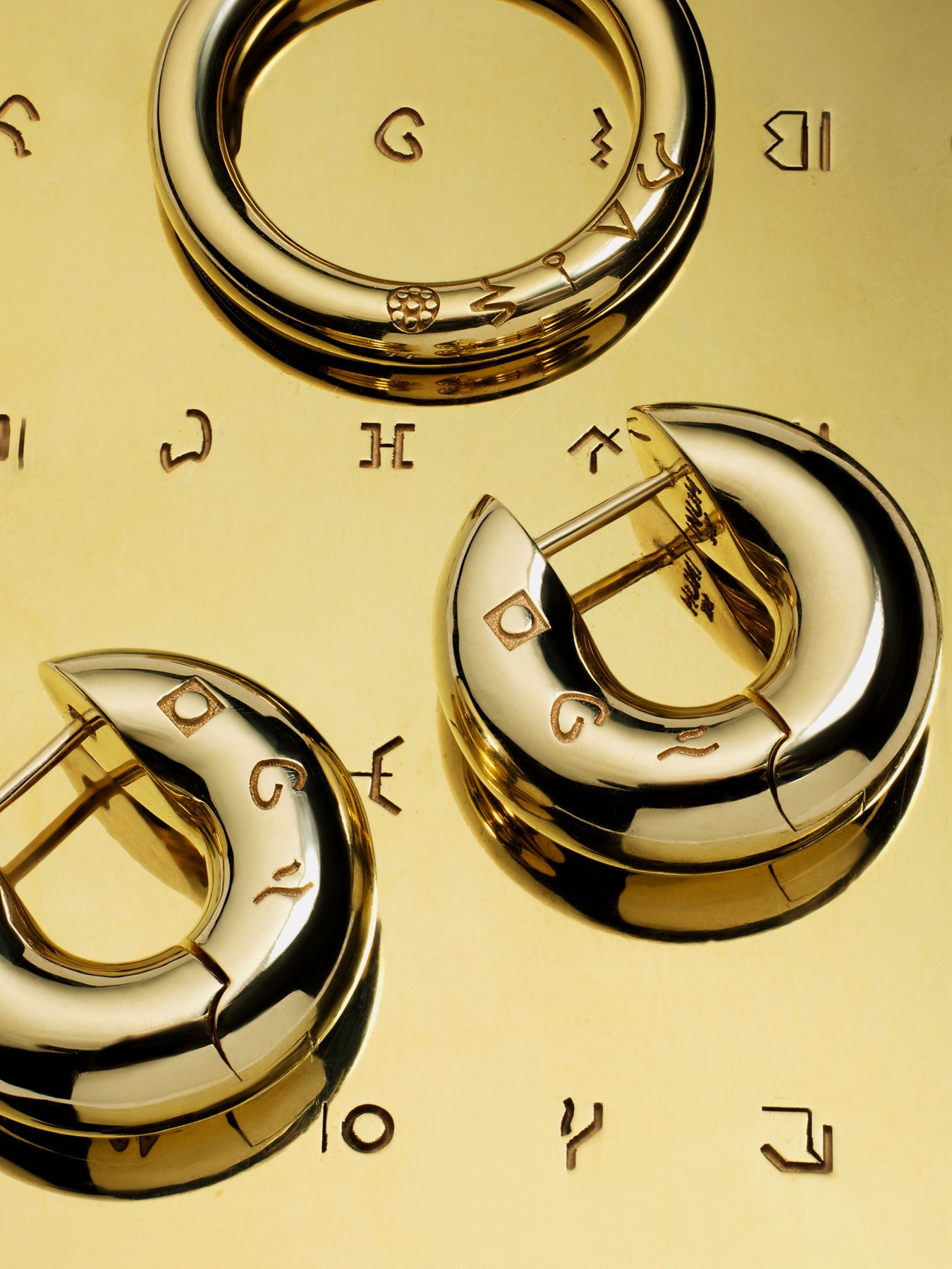 Gold ring and earrings with engraved symbols on a gold background