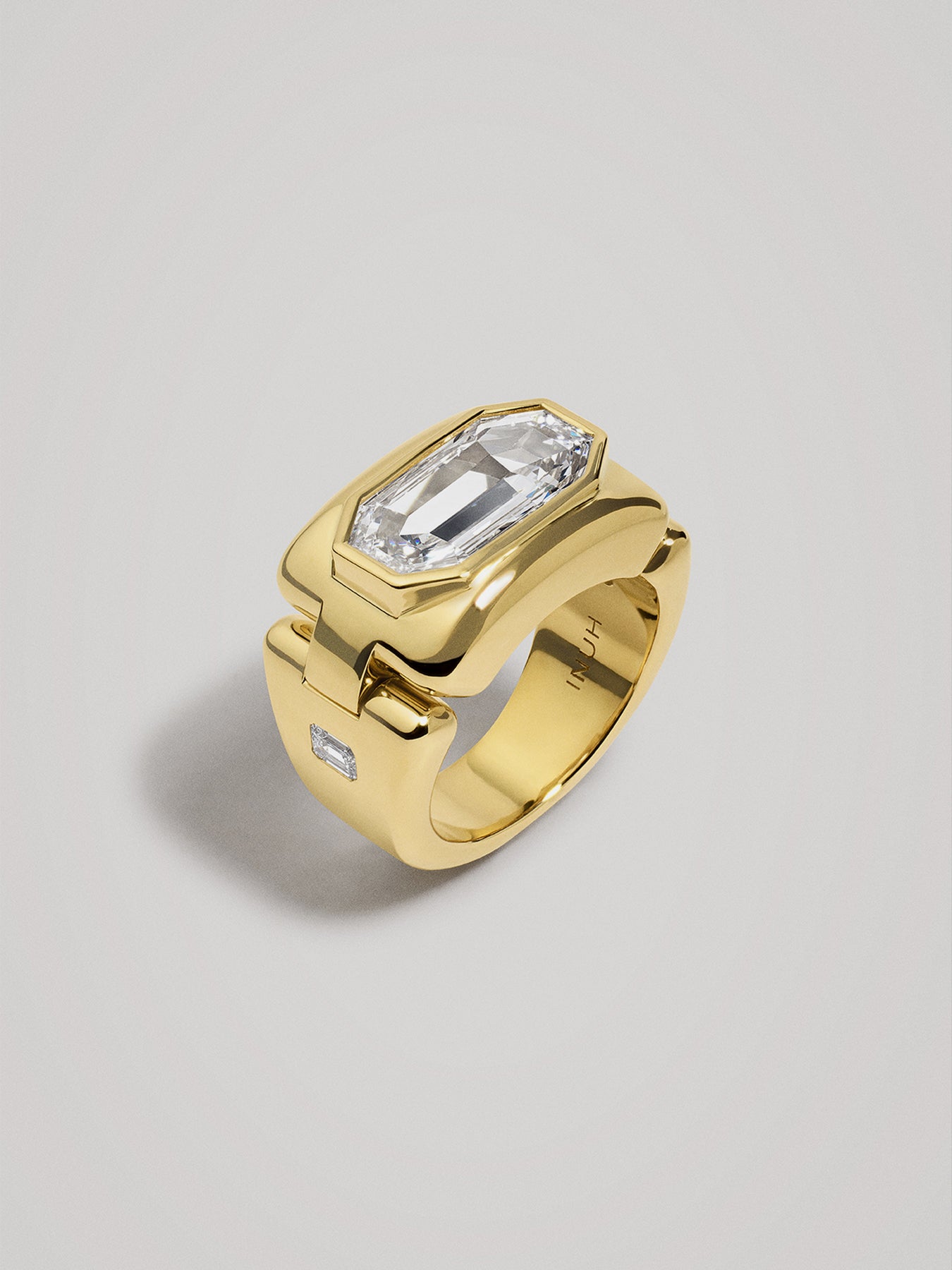 Gold ring with a large rectangular diamond on a gray background