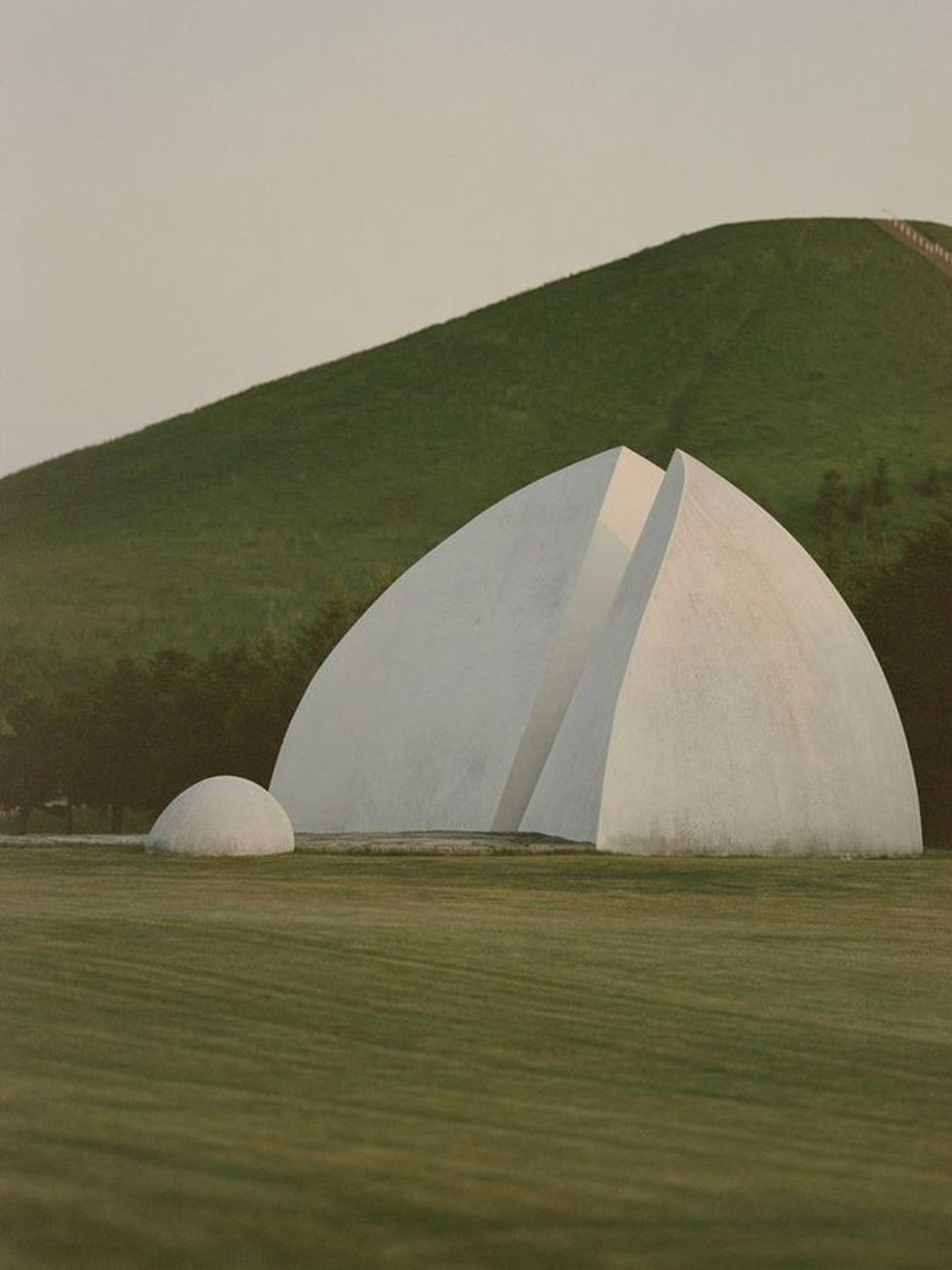 Modern architectural structure with curved design in a green landscape