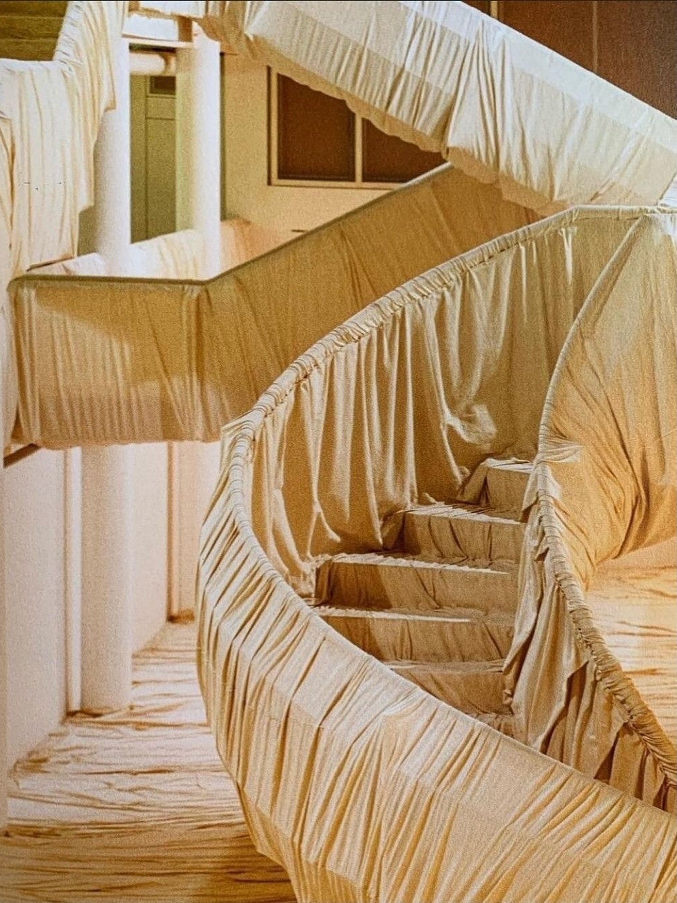Spiral staircase wrapped in beige fabric inside a building