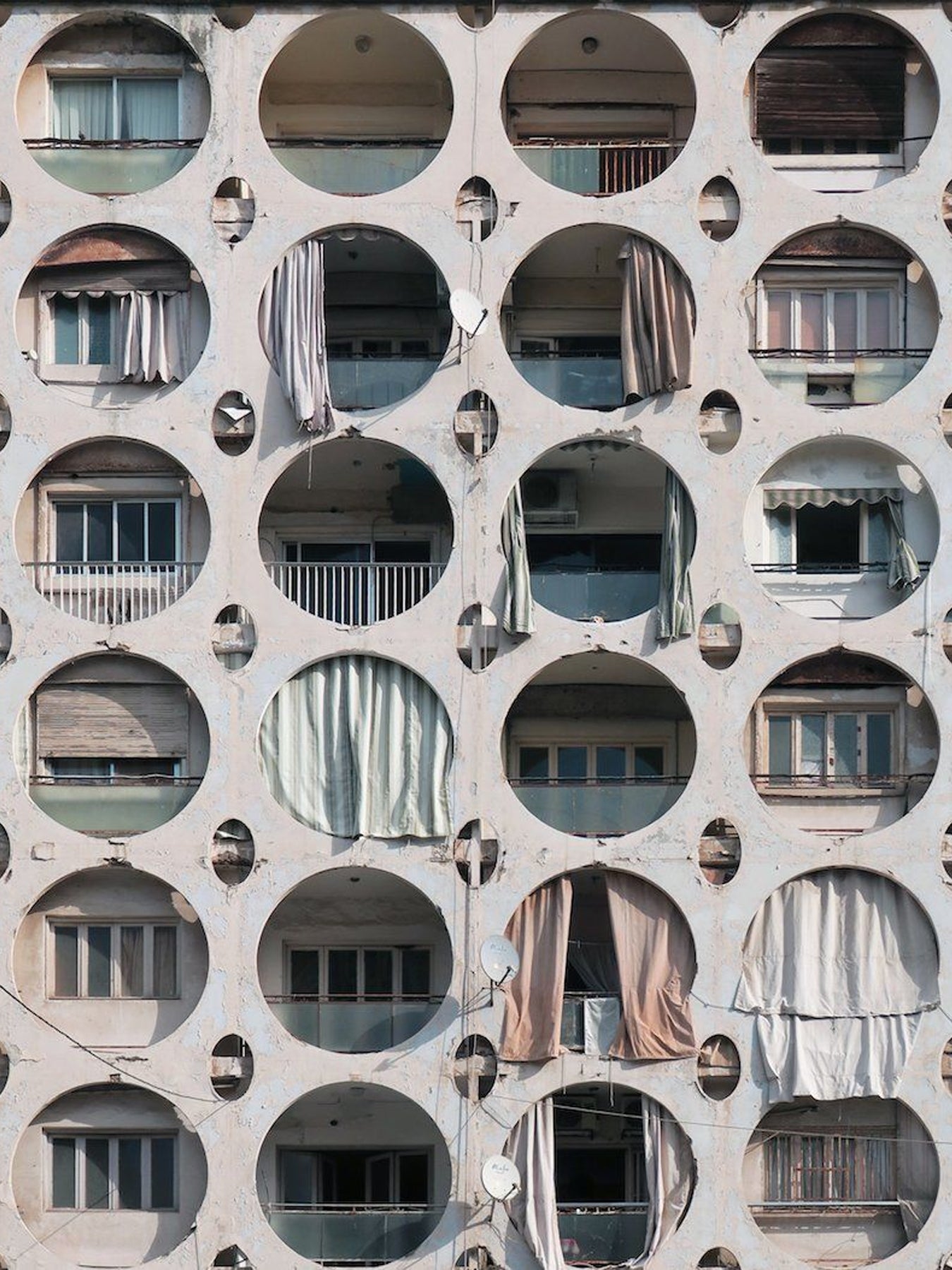 Pattern of circular windows and balconies on a building facade.
