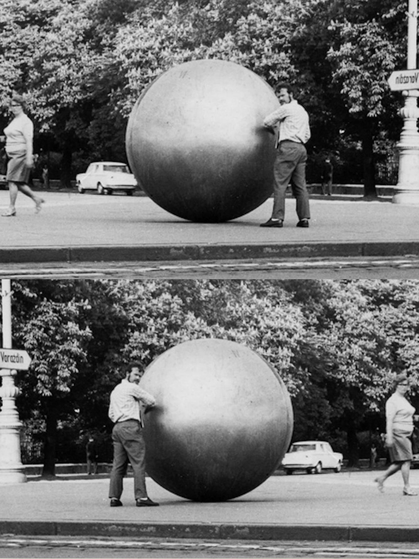 Two men standing by two large metallic spheres in a park setting.