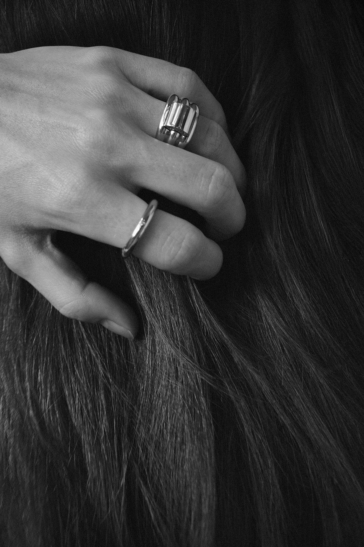 Close-up of a hand with multiple gold rings holding dark hair