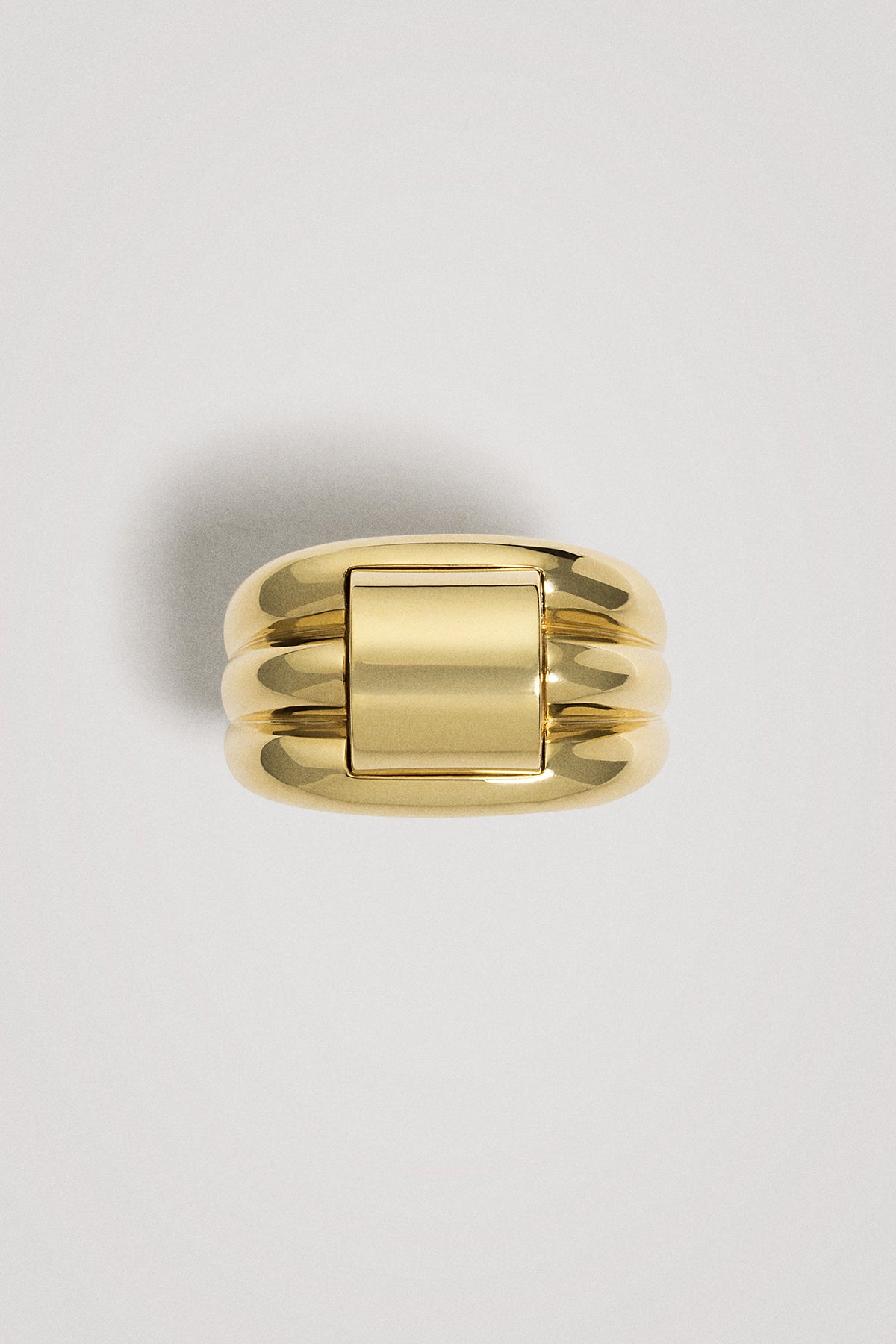 Gold ring with a ribbed design on a light gray background