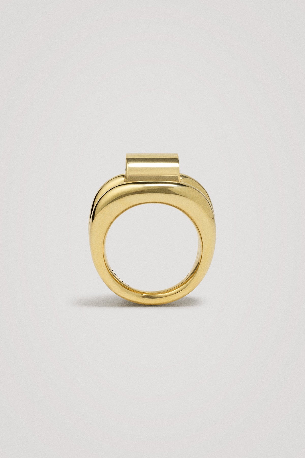 Gold ring with ribbed detail on a light gray background