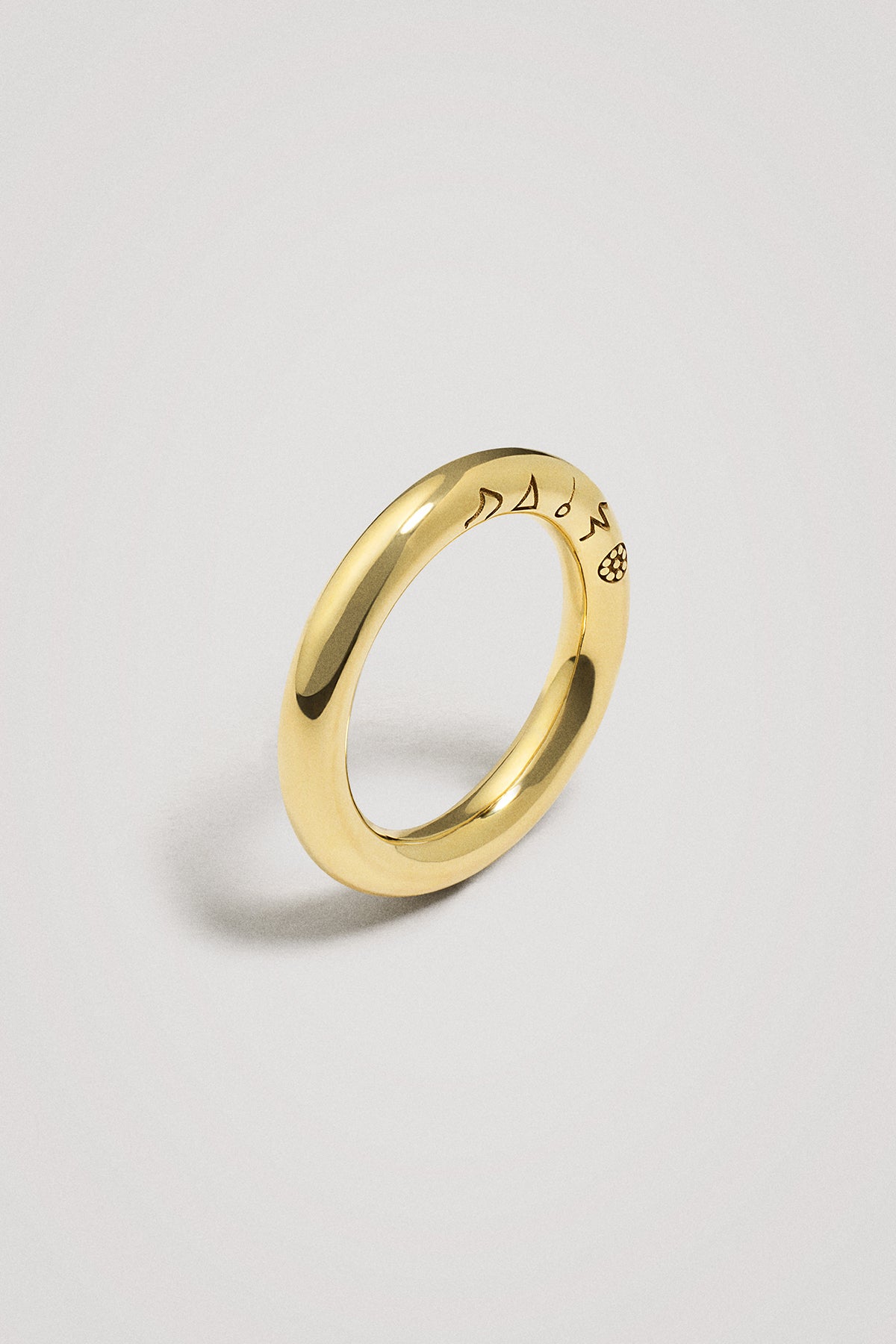 Gold ring with engraved symbols on a light gray background