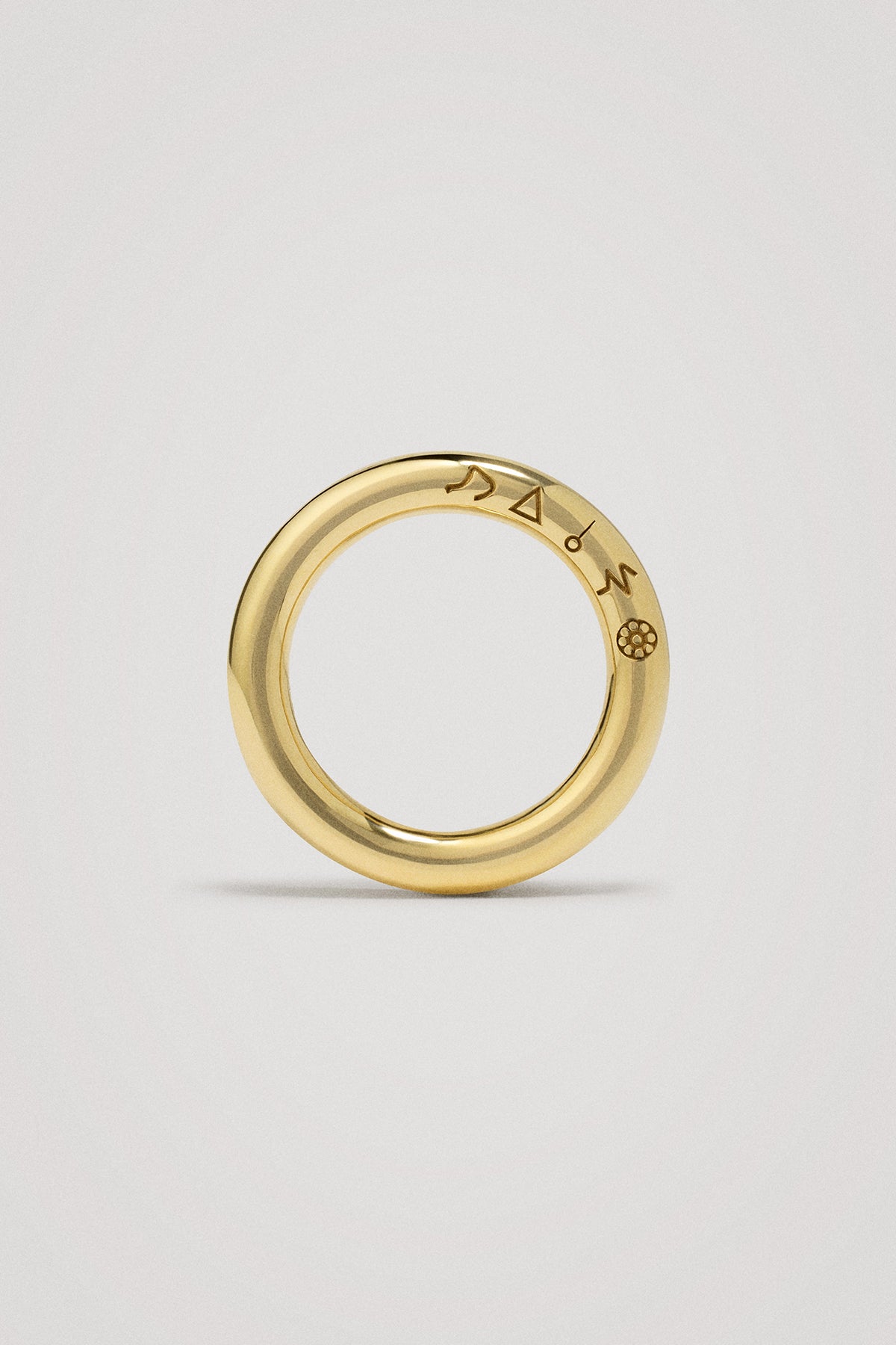 Gold ring with engraved symbols on a light gray background