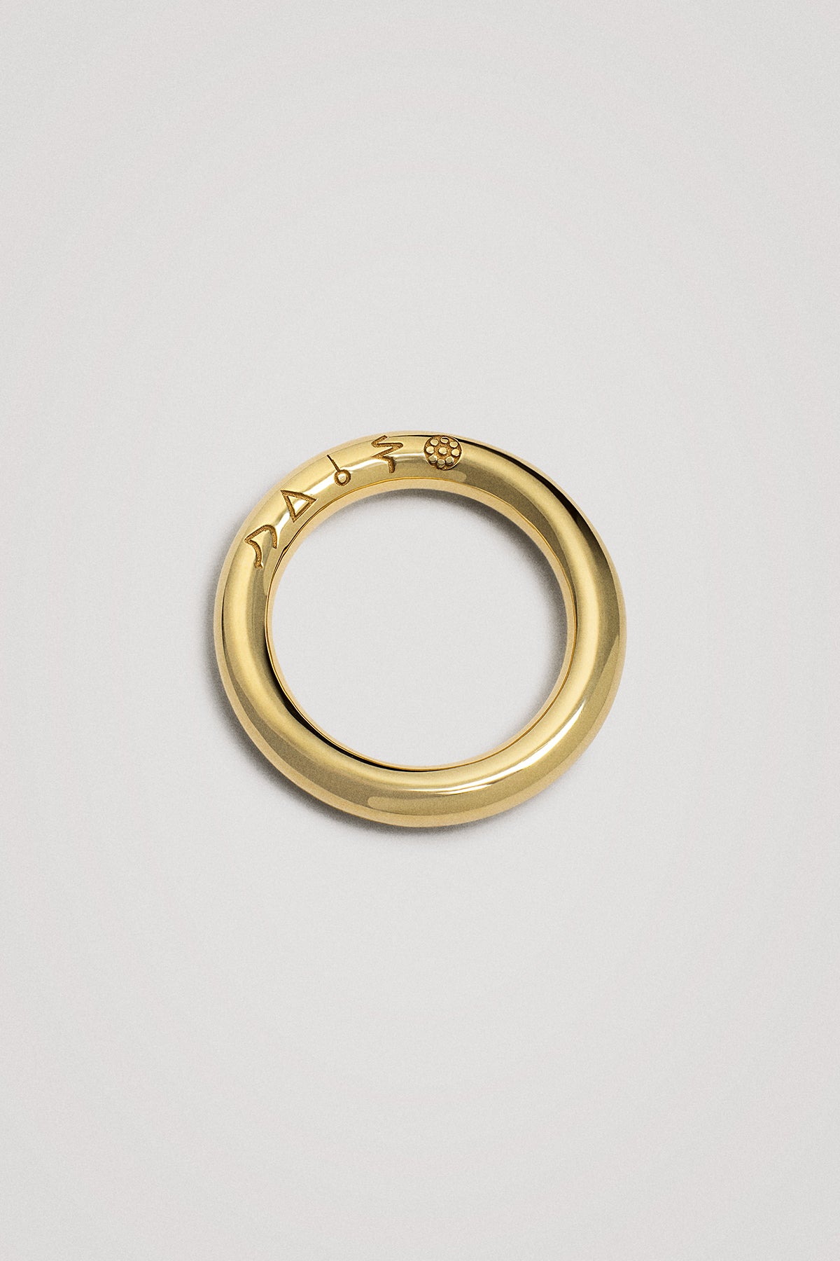 Gold ring with engraved design on a light gray background