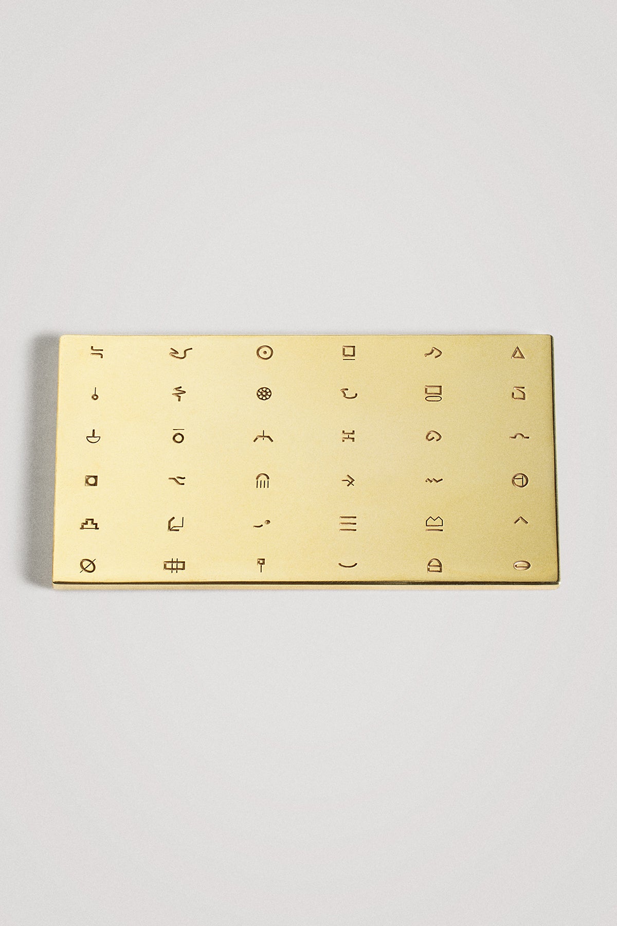 Gold rectangular object with symbols on a light gray background