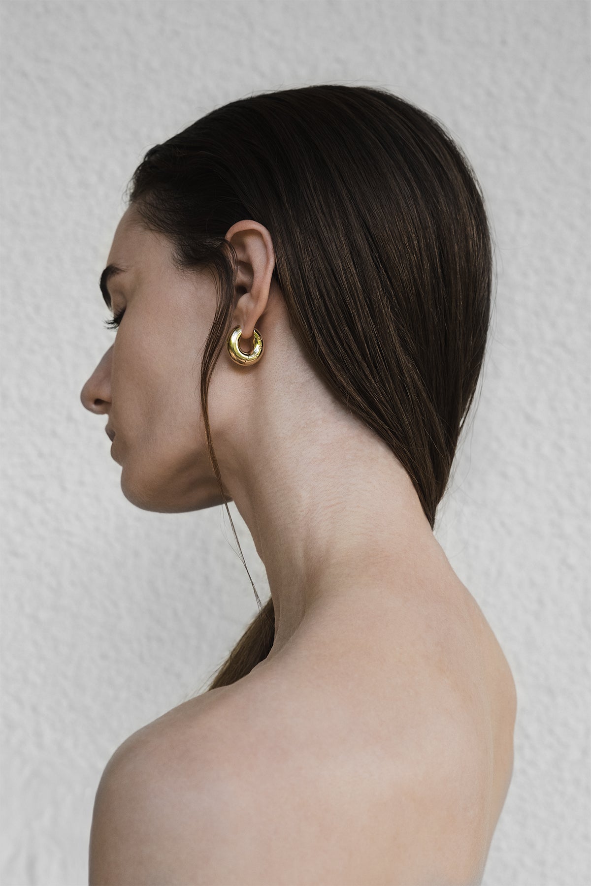 Woman wearing gold hoop earrings against a neutral background