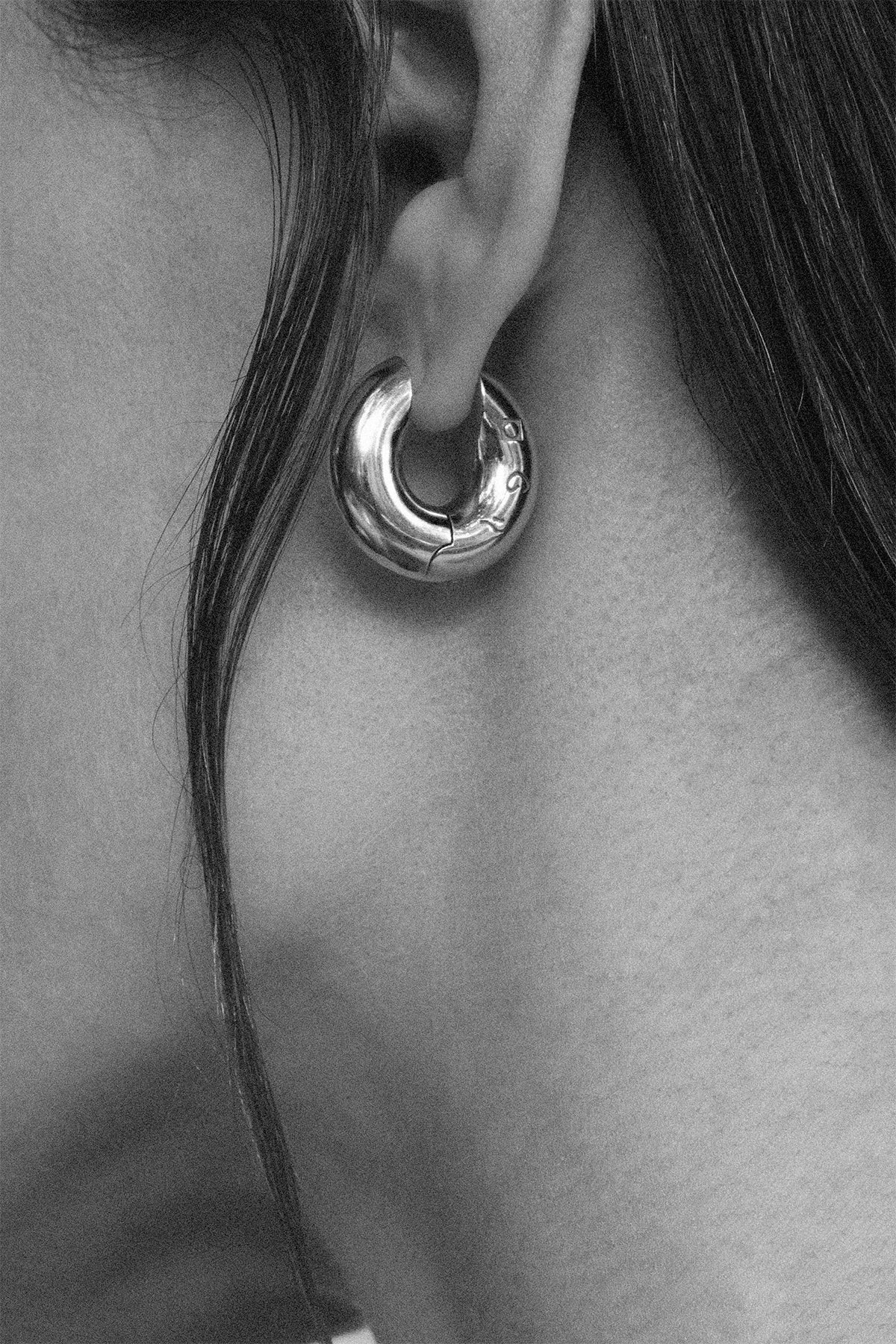 Close-up of a ID hoop earring worn by a person.