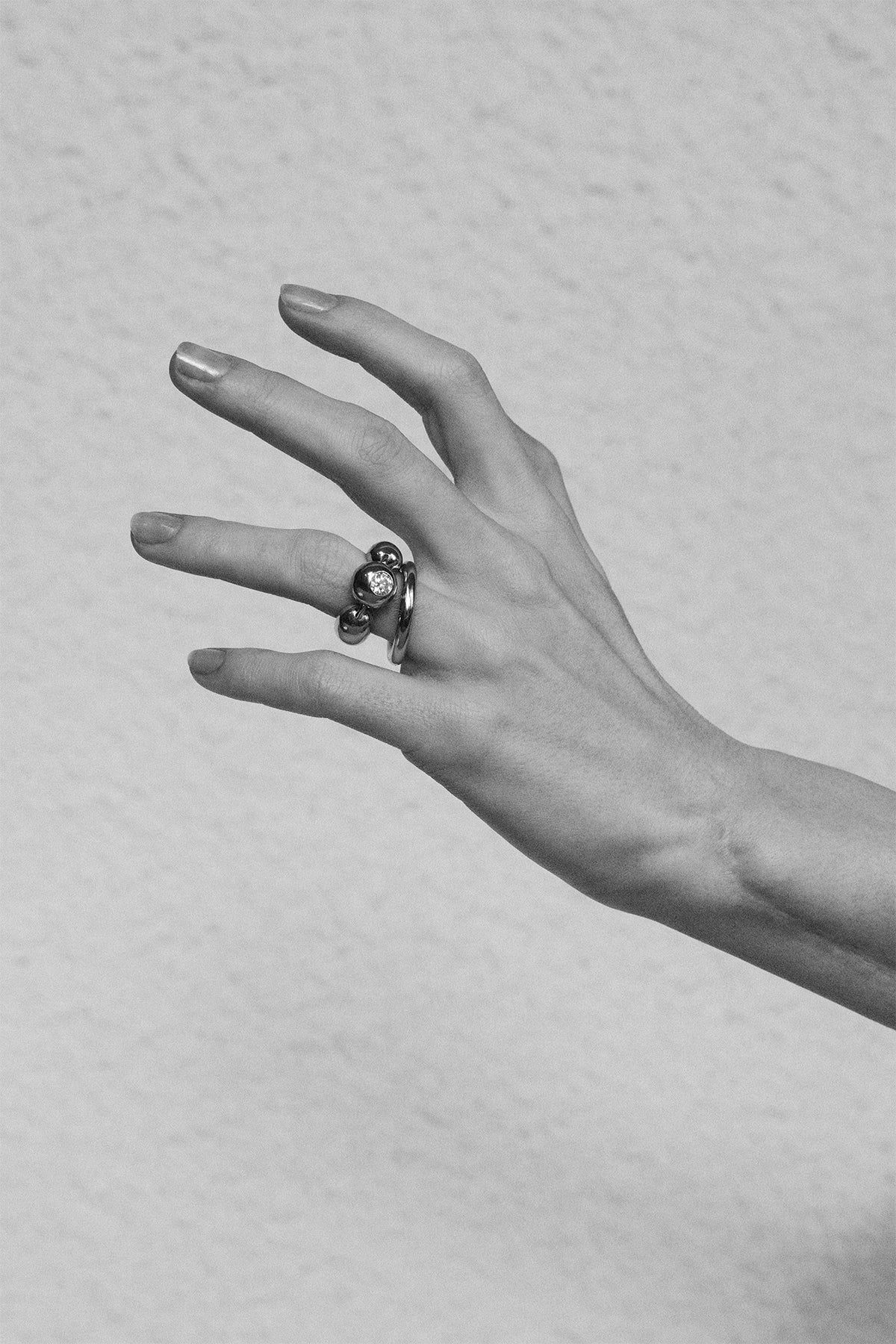 Hand wearing a ring with a diamond on a textured gray background
