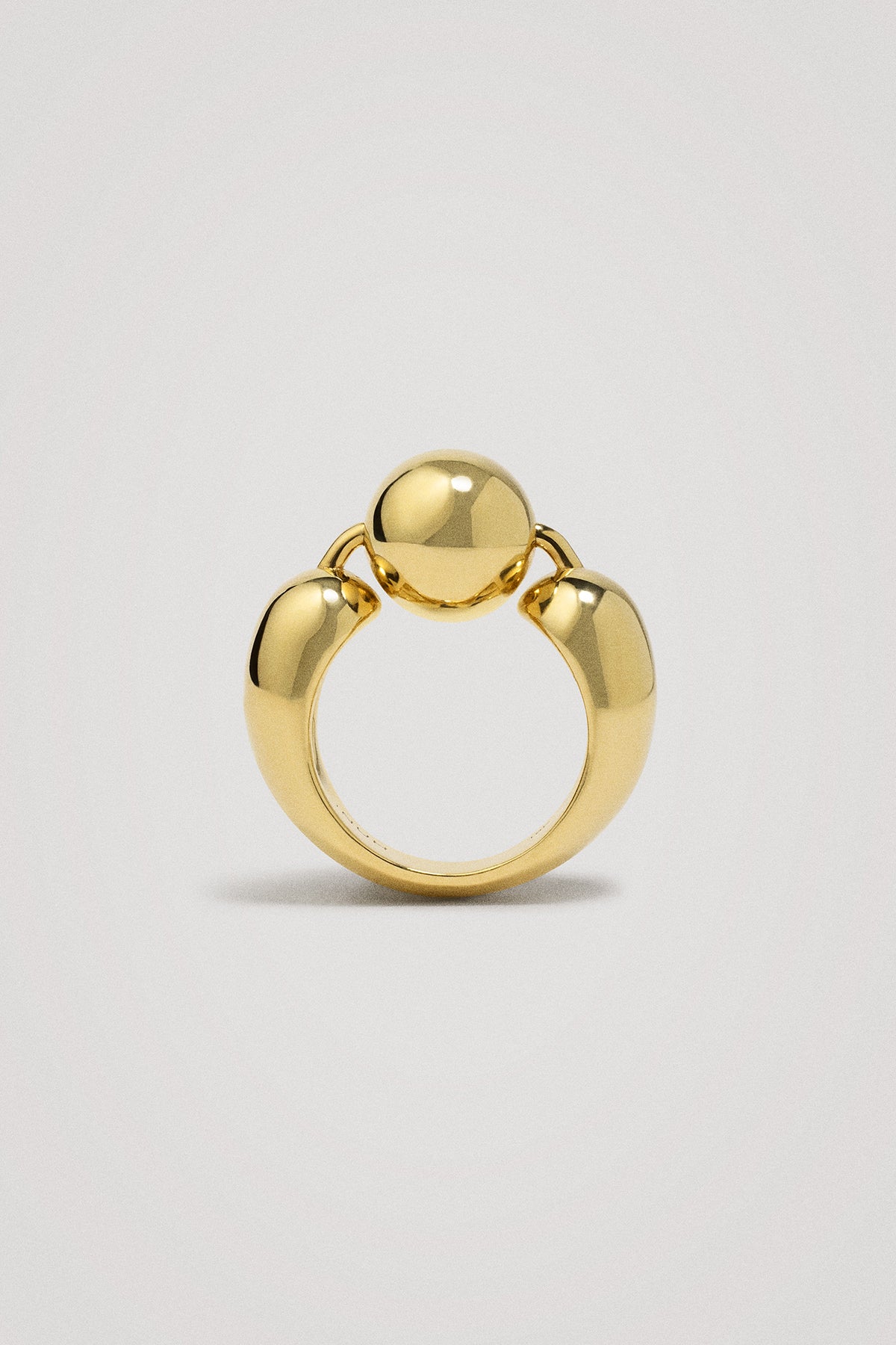 Gold ring with a unique design on a light gray background