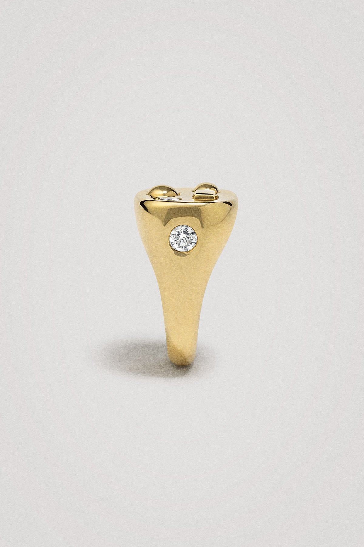 Chunky gold ring with a diamond on a light gray background
