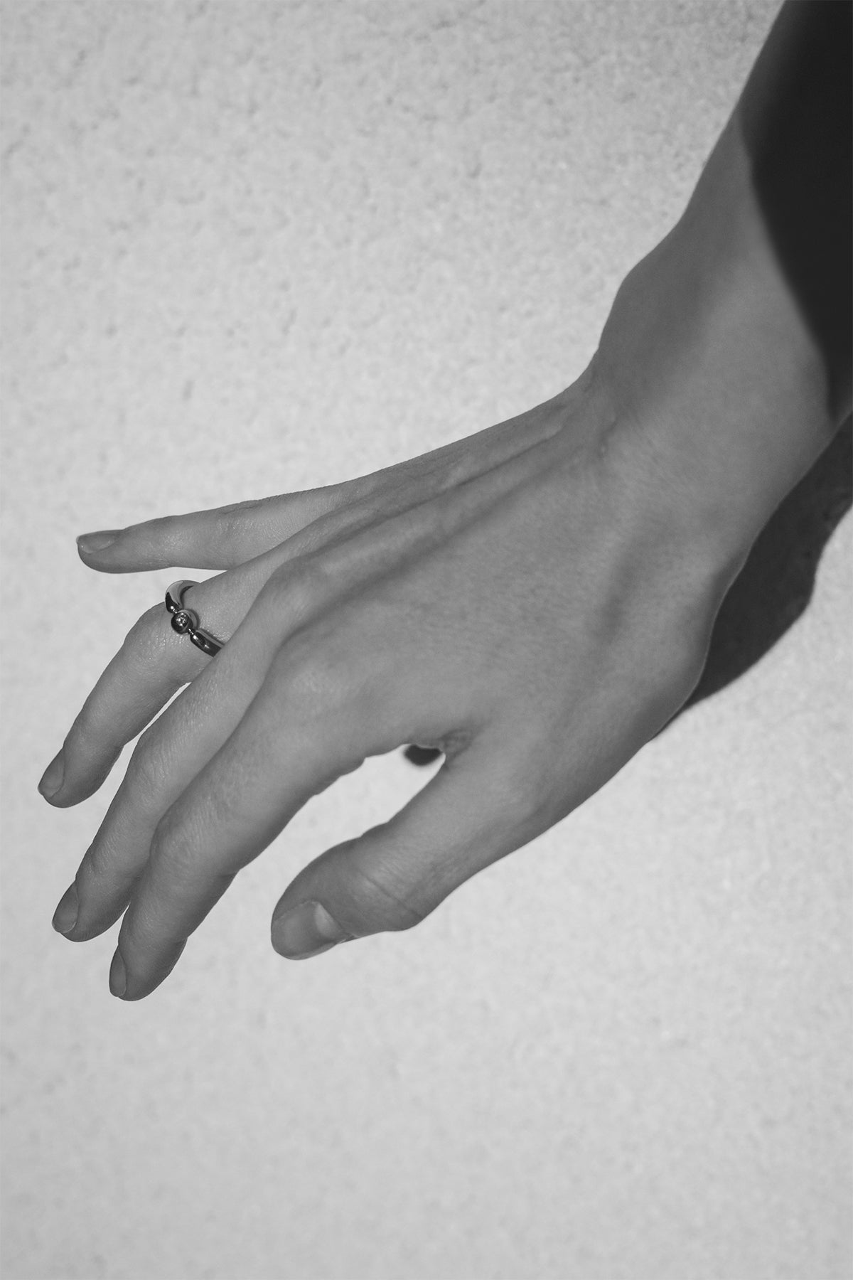 Close-up of a hand with a ring on a textured gray background