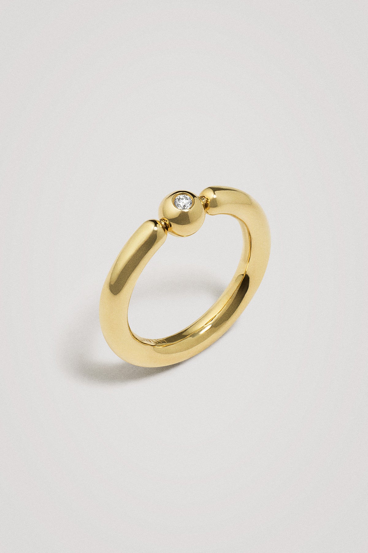 Gold ring with a small diamond on a light gray background