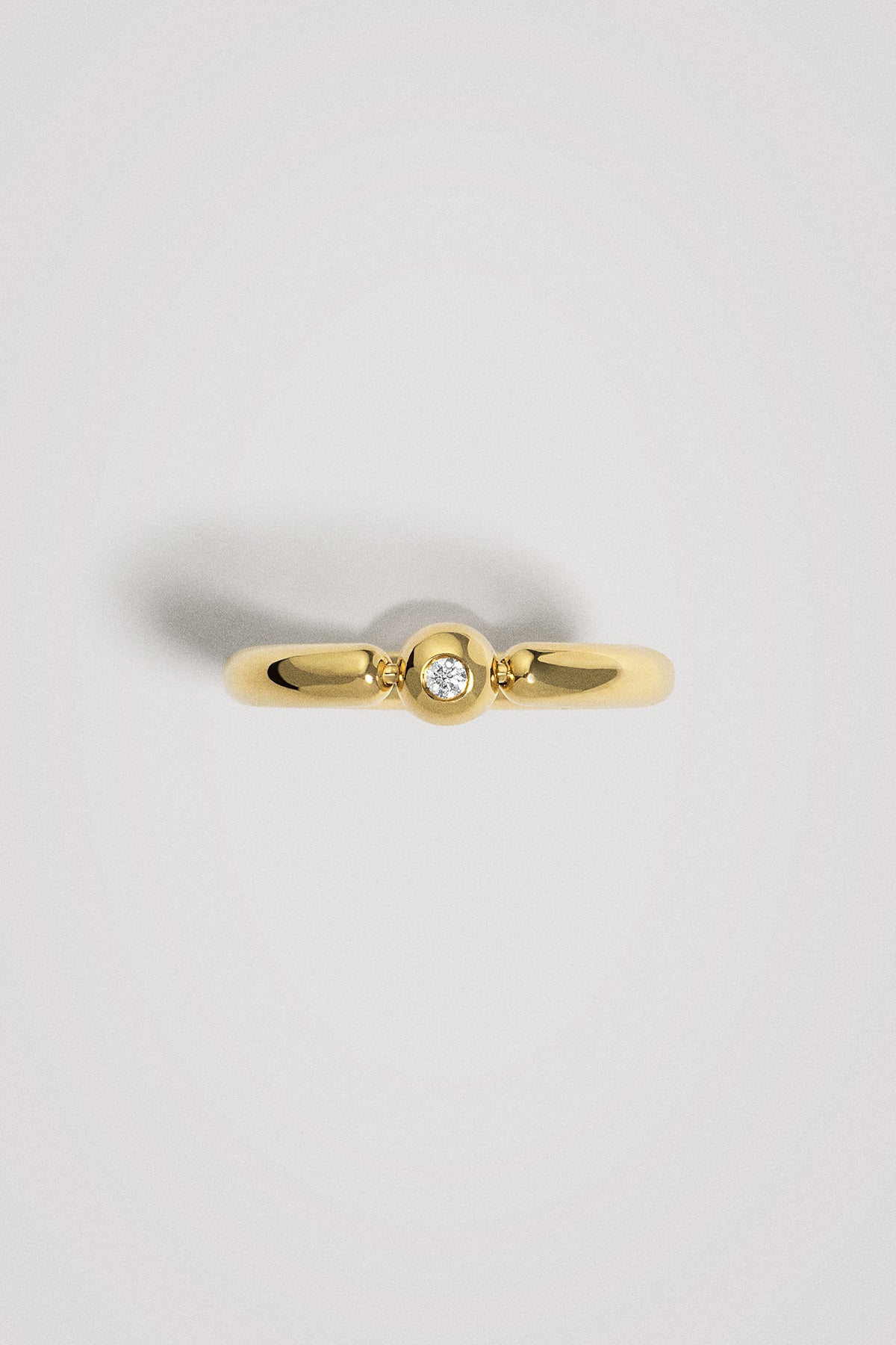 Gold ring with a small diamond on a light gray background