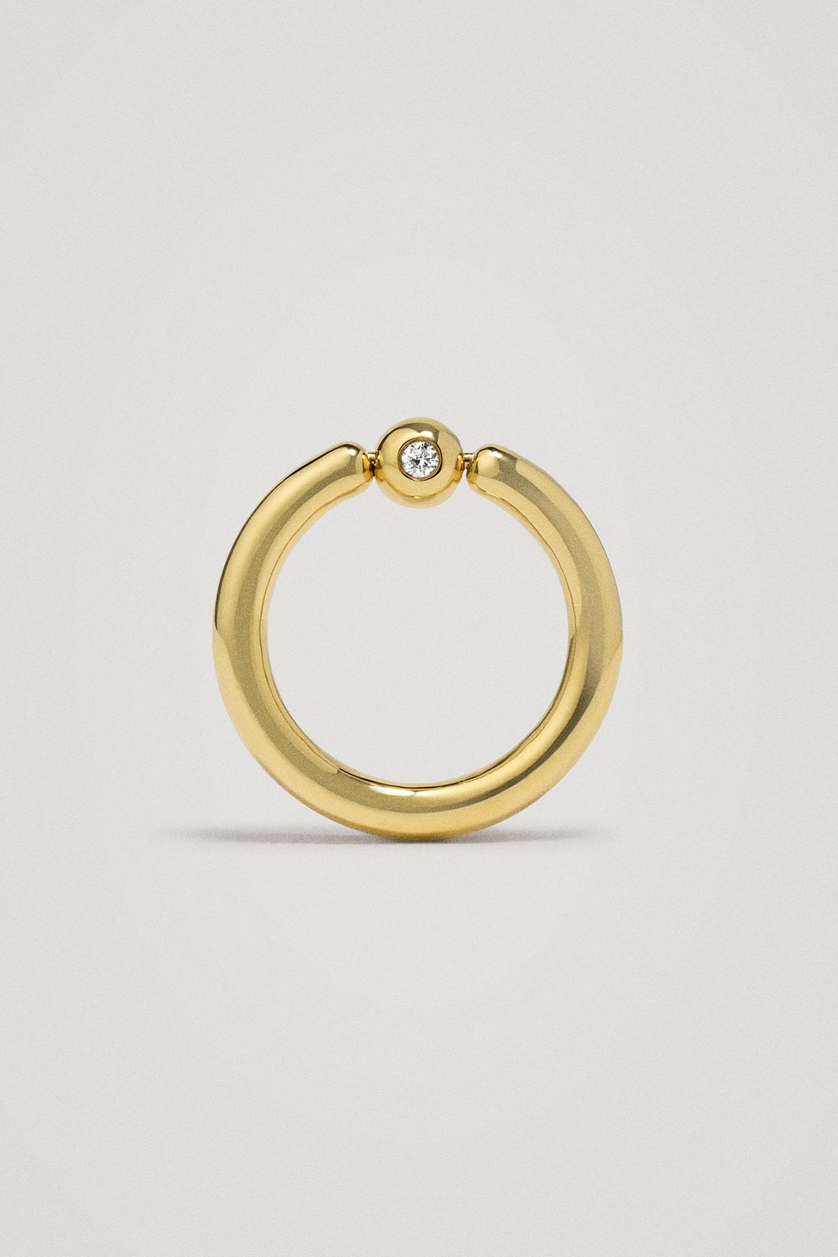 Gold ring with a small diamond on a light gray background